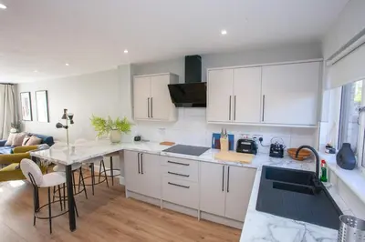 a kitchen with white cabinets and a table with chairs at Stylish and Modern 2 Bed House in Glasgow