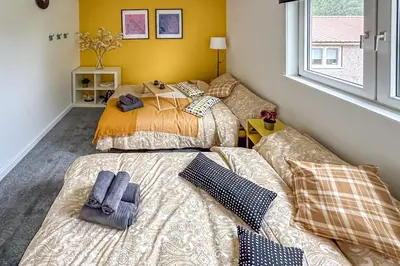 two beds in a room with yellow walls at Quite Charming house near Glasgow in Clydebank