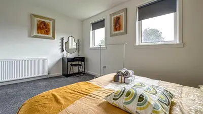 a bedroom with a bed and two windows and a mirror at Quite Charming house near Glasgow in Clydebank