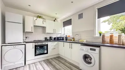 a kitchen with white cabinets and a washer and dryer at Quite Charming house near Glasgow in Clydebank