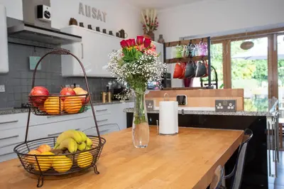 a kitchen with a table with baskets of fruit and flowers at The Banking Hall in Polmont