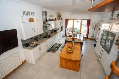 a kitchen with white cabinets and a wooden table at The Banking Hall in Polmont