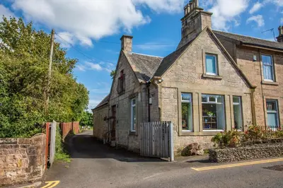 an old stone house with a fence in front of it at The Banking Hall in Polmont
