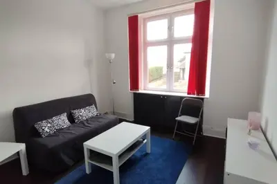 a living room with a black couch and a window at Lovely flat near Glasgow in Barrhead