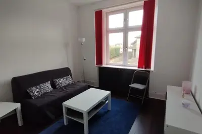 a living room with a black couch and a window at Lovely flat near Glasgow in Barrhead