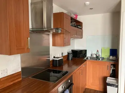a kitchen with wooden cabinets and a stove top oven at Duplex Apartment in Glasgow