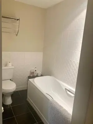 a bathroom with a white tub and a toilet at Duplex Apartment in Glasgow
