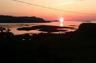 a sunset over a body of water with the sun setting at Little cottage-Village of Bunessan-Sleeps4 in Bunessan