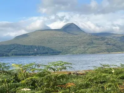 a mountain in the middle of a body of water at Little cottage-Village of Bunessan-Sleeps4 in Bunessan