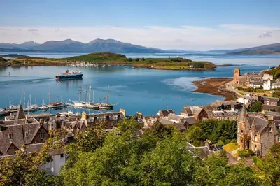 a boat is docked in a harbor next to a town at Exceptional 2BD Apt - next to ferry & train station in Oban