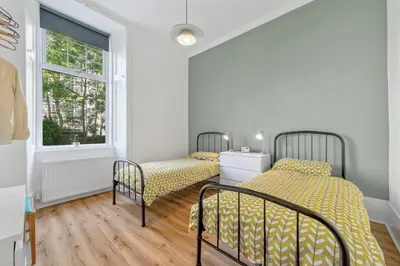 two beds in a room with a window at Woodford Street in Mansewood