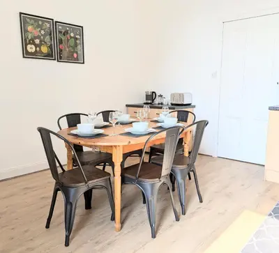 a dining room table with black chairs and a kitchen at Campbeltown Retreat in Campbeltown