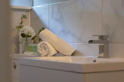 a bathroom sink with a towel and a vase of flowers at Cosy Palm Studio West End - Pass the Keys in Glasgow