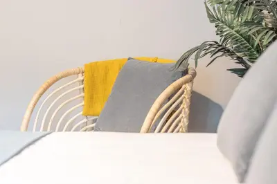 a wicker chair with a gray and yellow pillow on it at Cosy Palm Studio West End - Pass the Keys in Glasgow