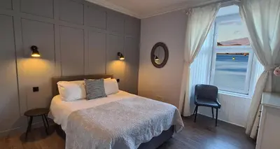 a bedroom with a bed and a window and a chair at Three Oban in Oban
