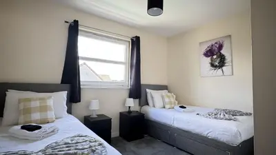 a bedroom with two beds and a window at Kingfisher Apartment in Dunfermline
