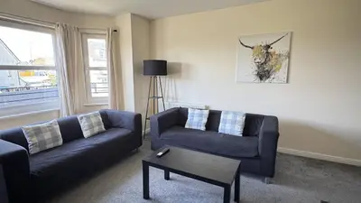 a living room with two couches and a table at Kingfisher Apartment in Dunfermline