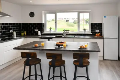 a kitchen with a large island with bar stools at Diamond House - 4 bedroom luxury home in Airdrie