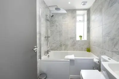 a bathroom with a tub and a toilet and a sink at Diamond House - 4 bedroom luxury home in Airdrie