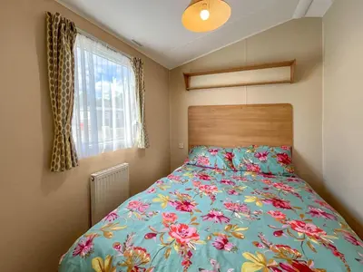 a bedroom with a bed with a floral bedspread at Peppy in Newton Stewart