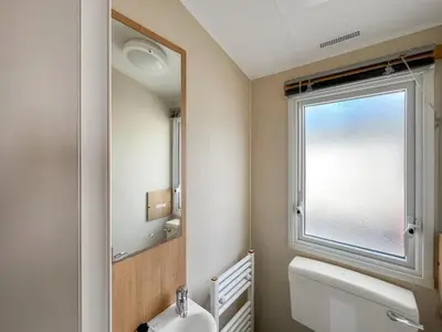 a bathroom with a mirror and a toilet and a window at Peppy in Newton Stewart