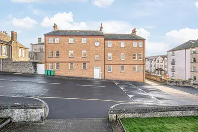 an empty street in front of a brick building at Super Prime Abbey Free Parking by TBA in Dunfermline