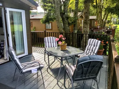 a patio with three chairs and a table on a deck at Thistle Lodge in Dollar