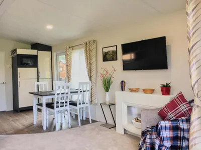 a living room with a table and chairs and a tv at Thistle Lodge in Dollar