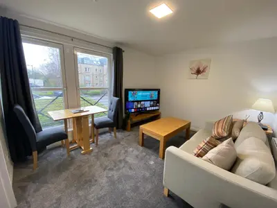 a living room with a couch and a table and a tv at Prime City Centre - Ground Floor Parking by TBA in Dunfermline