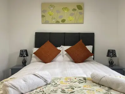 a bedroom with a bed with white sheets and pillows at Prime City Centre - Ground Floor Parking by TBA in Dunfermline