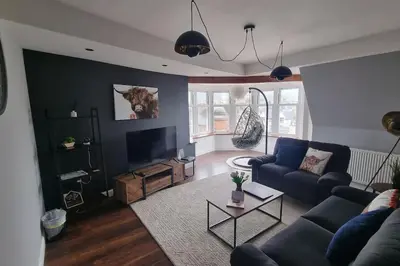 a living room with a blue couch and a tv at Mafeking Place Apartment in Campbeltown