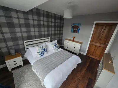 a bedroom with a bed with blue and white pillows at Mafeking Place Apartment in Campbeltown