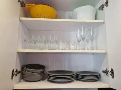 a cupboard filled with glasses and plates and bowls at Mafeking Place Apartment in Campbeltown