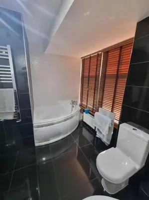 a bathroom with a toilet and a tub and a sink at Mafeking Place Apartment in Campbeltown
