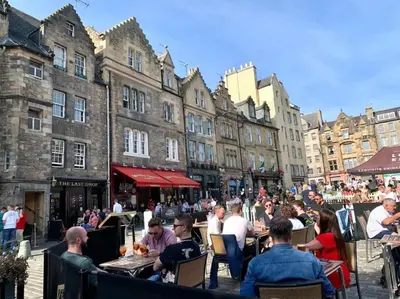 a group of people sitting at tables in front of buildings at Castle View Retreat in Edinburgh