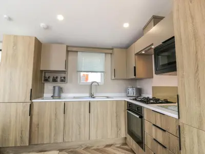 a kitchen with wooden cabinets and a sink at 11A Mansion View in Helensburgh