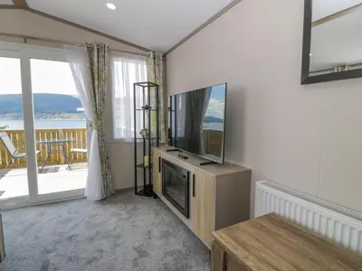 a living room with a tv and a large window at 11A Mansion View in Helensburgh