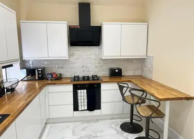 a kitchen with white cabinets and a wooden counter top at 3 Bed - Sleeps 7 - Free Parking - Central Location in Glasgow