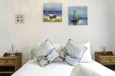 a bedroom with a bed with four paintings on the wall at Blackness Apartment in Linlithgow