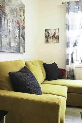 a living room with a yellow couch with pillows at Blackness Apartment in Linlithgow