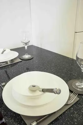 a white plate with a spoon on a table with glasses at Blackness Apartment in Linlithgow