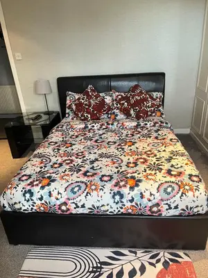 a bed with a floral comforter and pillows on it at Room in a Home in Edinburgh