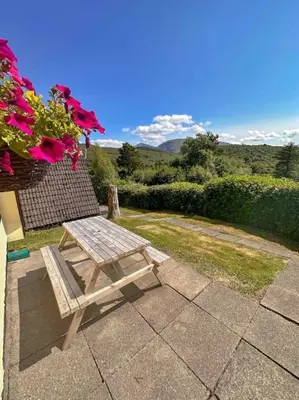 a wooden bench sitting on top of a patio at 1 Bedroom Cabin with Mountain & Loch Views - Quiet Location between Glencoe & Ben Nevis in Corran