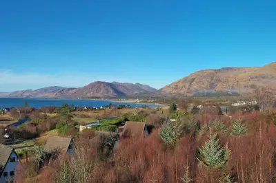 a town with a lake and mountains in the background at 1 Bedroom Cabin with Mountain & Loch Views - Quiet Location between Glencoe & Ben Nevis in Corran