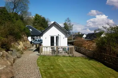 a white house with a fence and a yard at Highland Snug in Dunoon