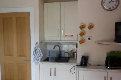 a kitchen with a sink and a clock on the wall at Highland Snug in Dunoon