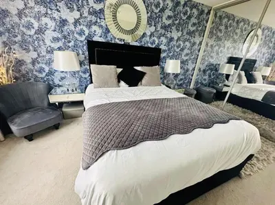 a bedroom with a bed and a chair and a mirror at Entire 4 bed perfect family home in Glasgow in Nitshill