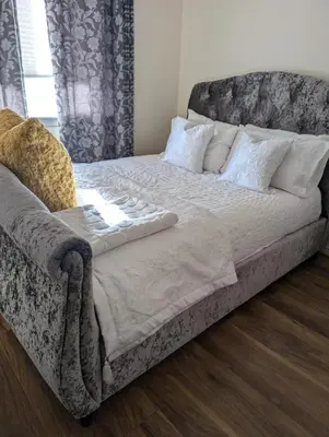 a large bed with white sheets and pillows at Holytown Homes in Holytown
