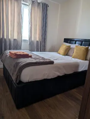 a large bed with a black frame in a bedroom at Holytown Homes in Holytown