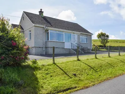 a house with a fence in front of it at Lilybank Cottage in Doularg